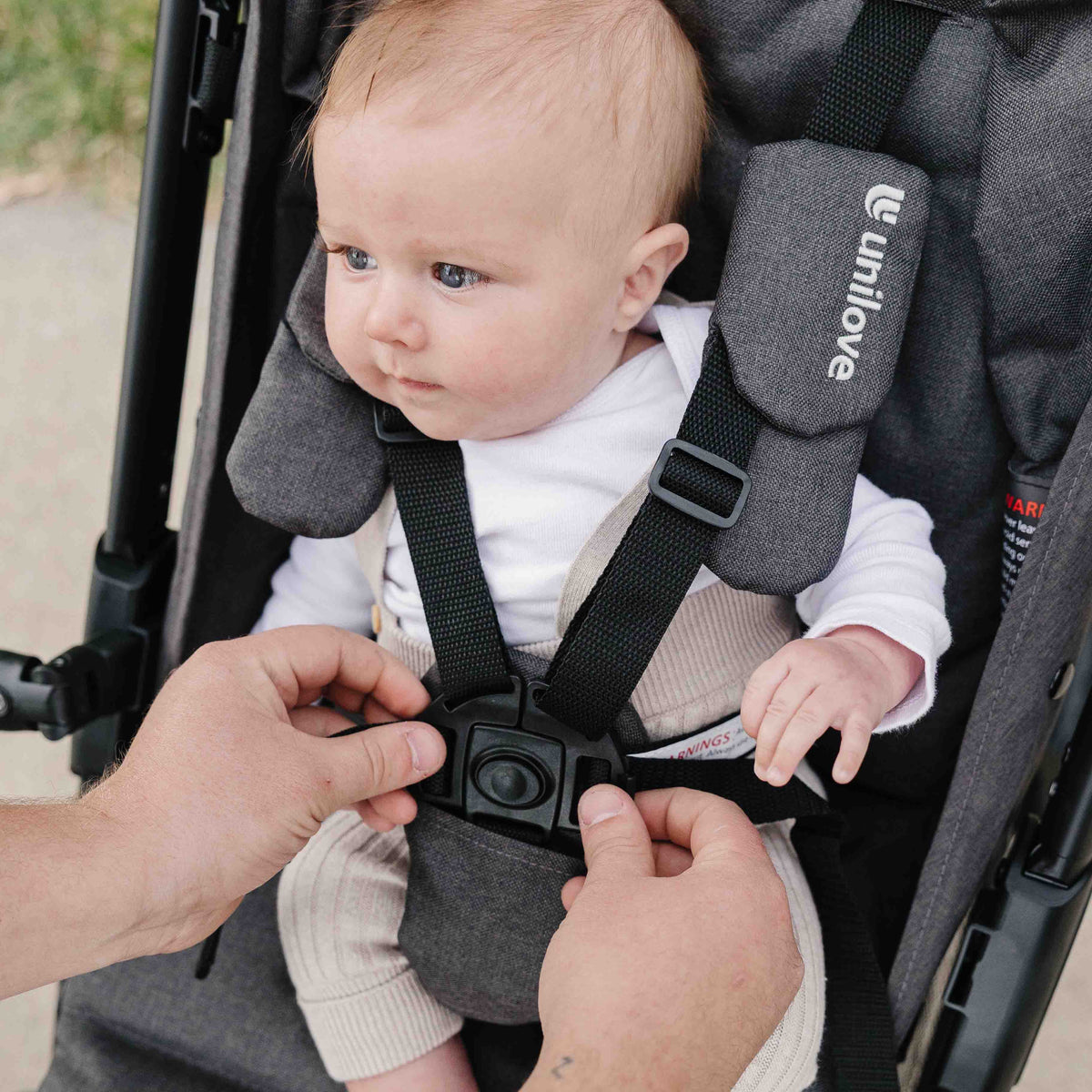 Baby being secured in a stroller with 'unilove' branding