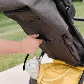 Person adjusting a stroller seat with a grassy background