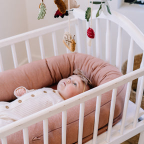Baby lying in a crib with decorative mobile above