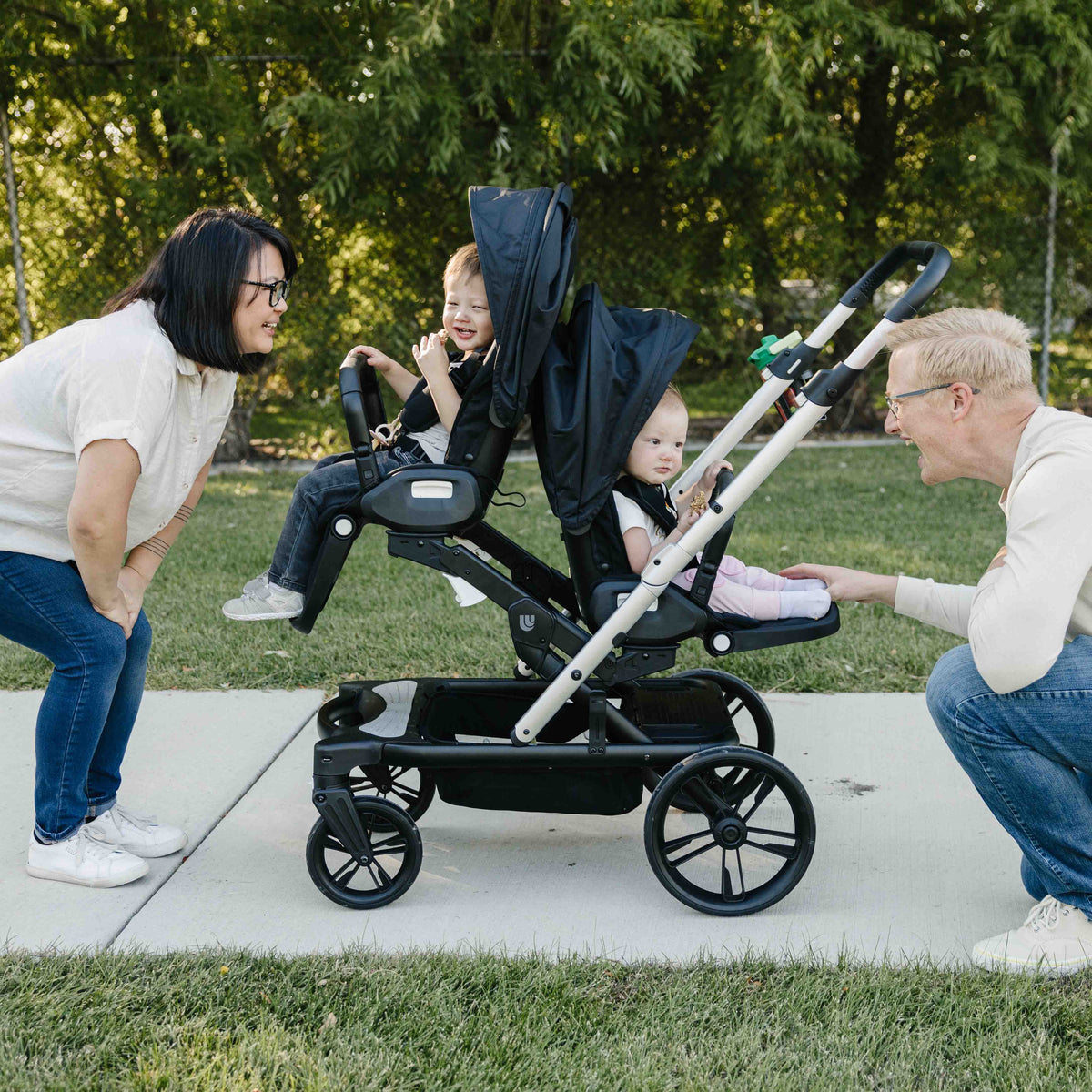 Two adults with a child in a stroller outdoors on a sunny day.