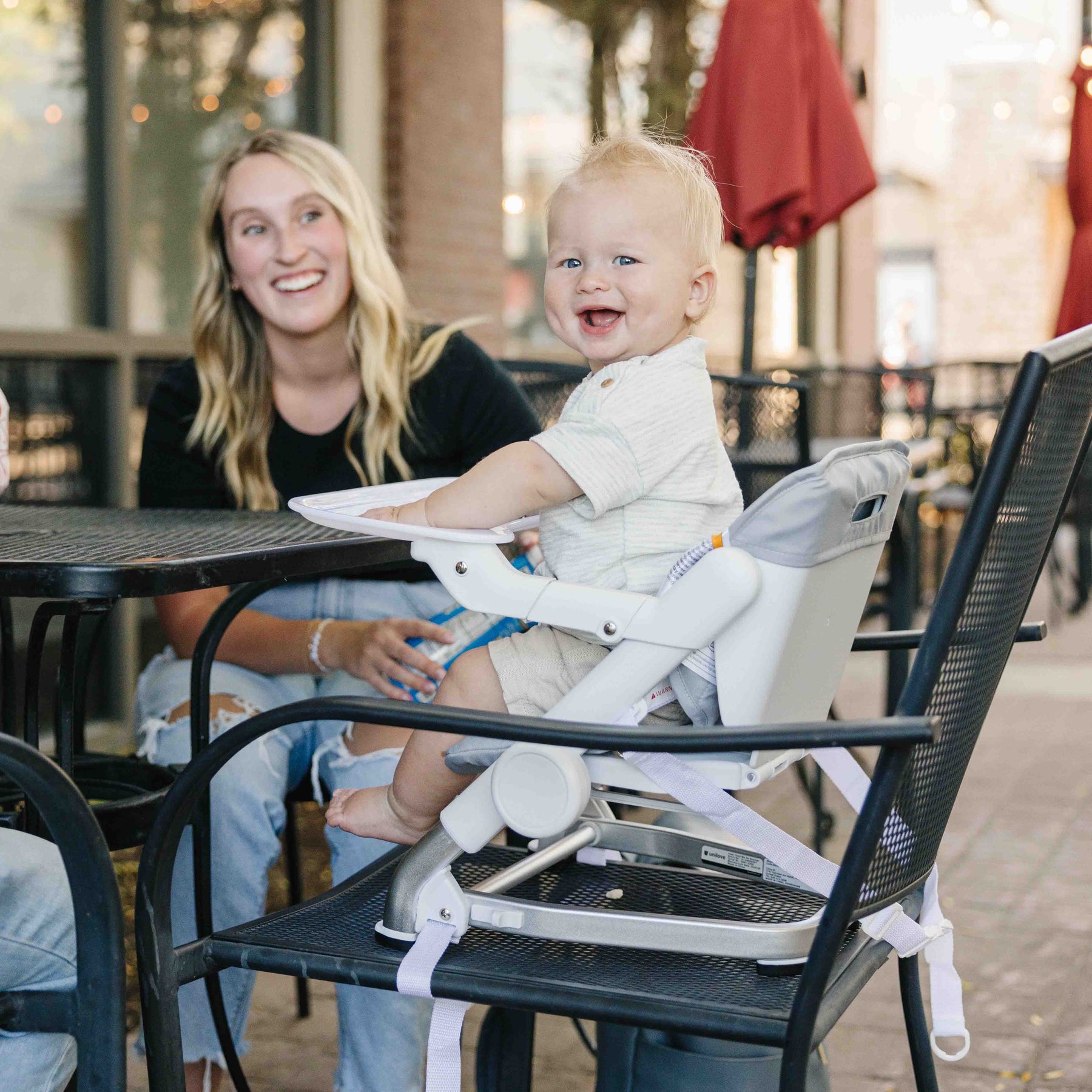 Woman with a child in a high chair at an outdoor dining area