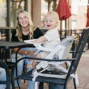 Woman with a child in a high chair at an outdoor dining area