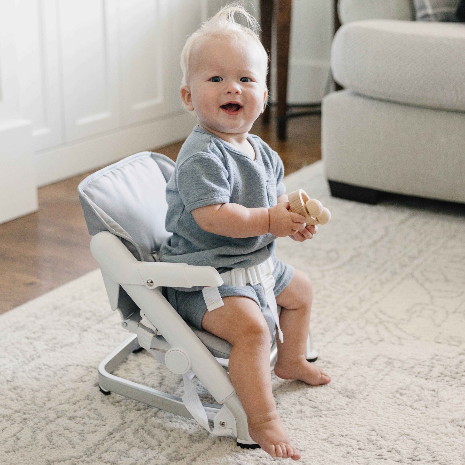 Baby sitting on a white and gray chair in a home setting