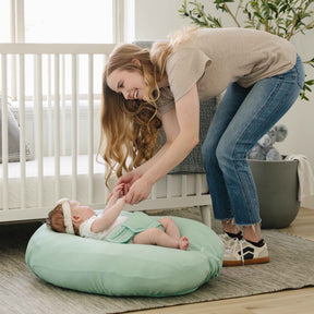 Woman interacting with a baby on a green cushion in a home setting