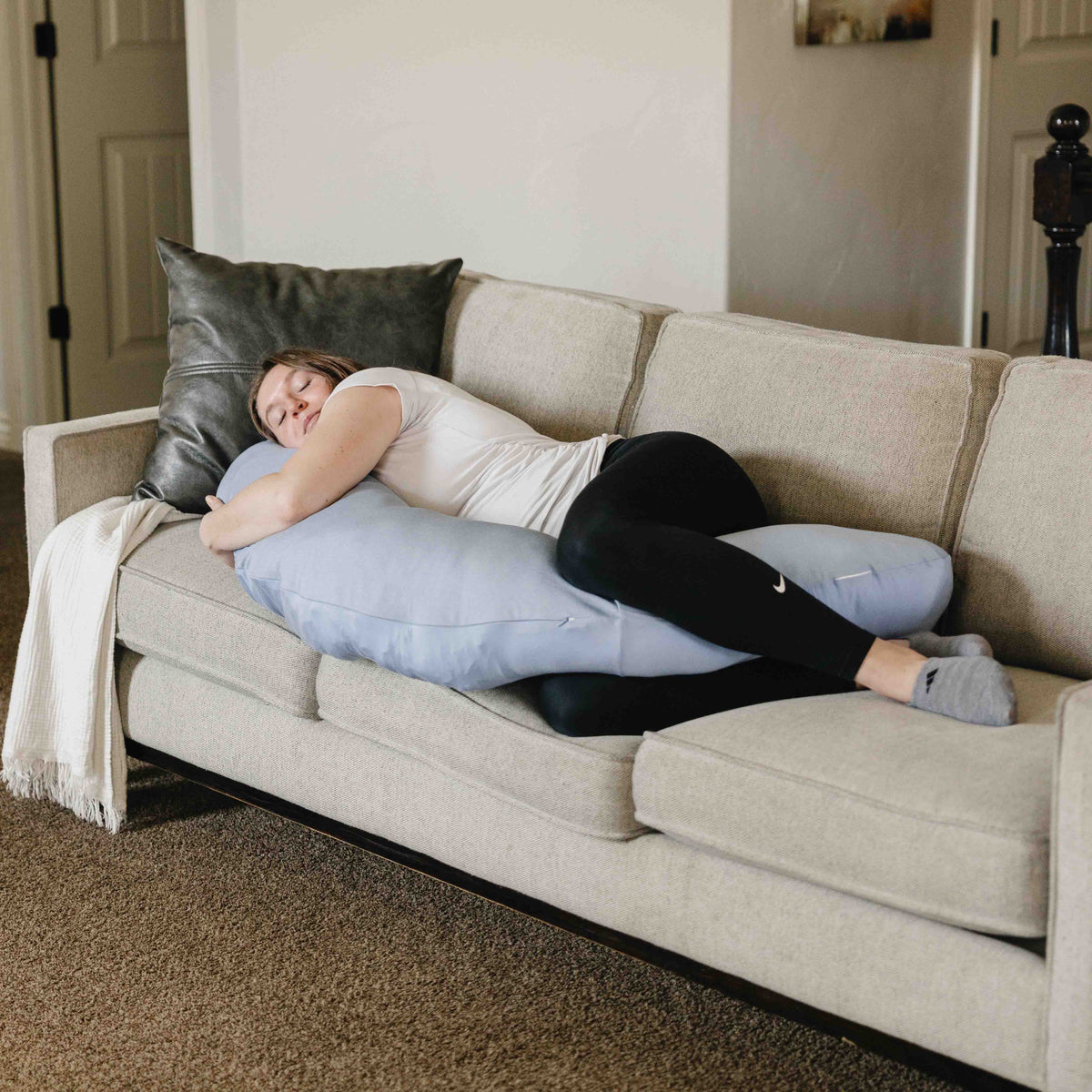 Person lying on a couch with a large pillow for support